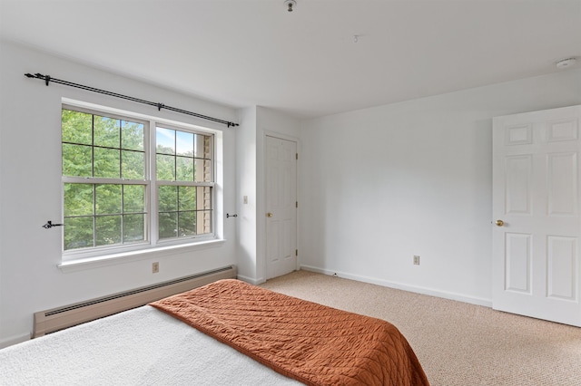 carpeted bedroom with baseboard heating and baseboards