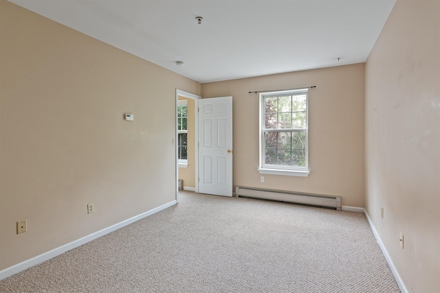 spare room with a baseboard radiator, baseboards, and light colored carpet