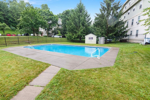 view of swimming pool with an outbuilding, fence, and a lawn