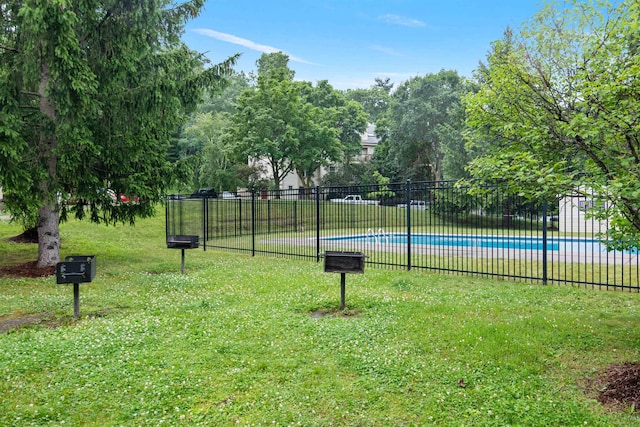 view of community with a yard, a swimming pool, and fence