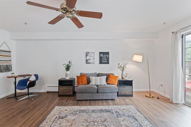 living area with a baseboard radiator, baseboards, and wood finished floors