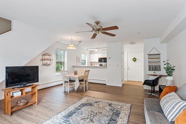 living area featuring a baseboard radiator, wood finished floors, a ceiling fan, and baseboards