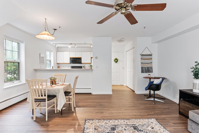 dining space featuring track lighting, a baseboard radiator, baseboards, and wood finished floors