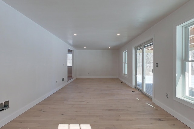 empty room with light wood finished floors, visible vents, baseboards, and recessed lighting