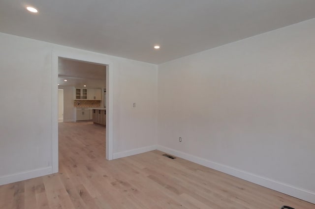 unfurnished room featuring light wood-style floors, baseboards, visible vents, and recessed lighting