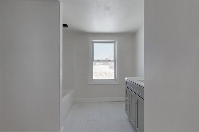 bathroom with a tub to relax in, baseboards, and vanity