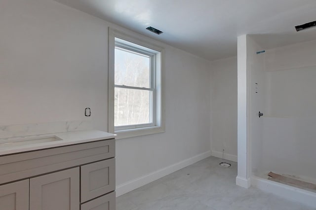 full bathroom with a stall shower, vanity, and baseboards