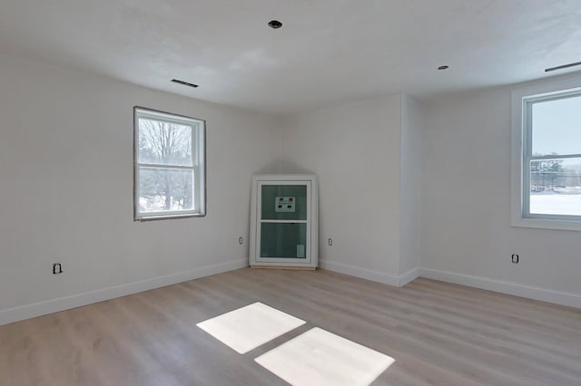 spare room with light wood-type flooring, a wealth of natural light, and baseboards