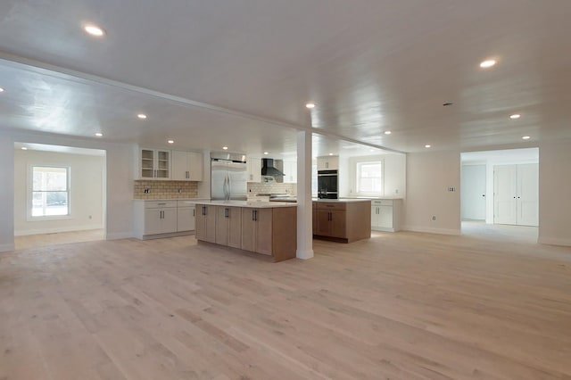 kitchen with built in fridge, a spacious island, white cabinets, open floor plan, and light countertops