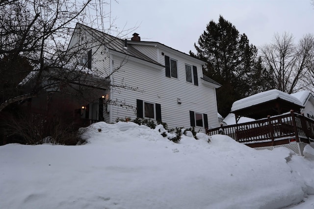 snow covered back of property featuring a chimney and a deck