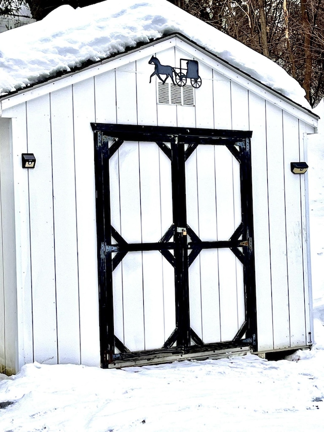 snow covered structure with a shed and an outdoor structure