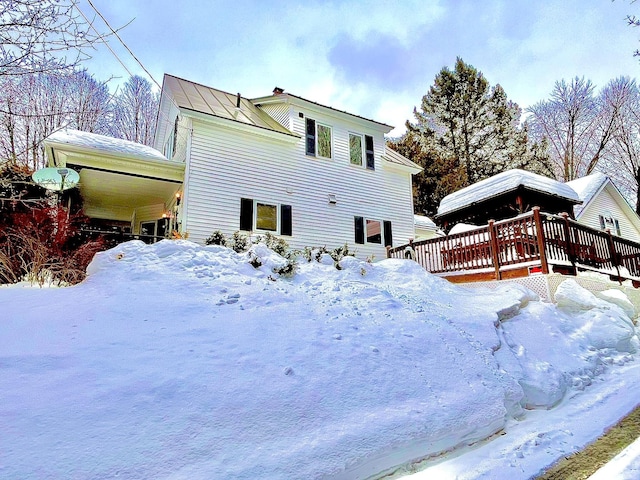 view of snow covered exterior with a standing seam roof, a deck, and metal roof