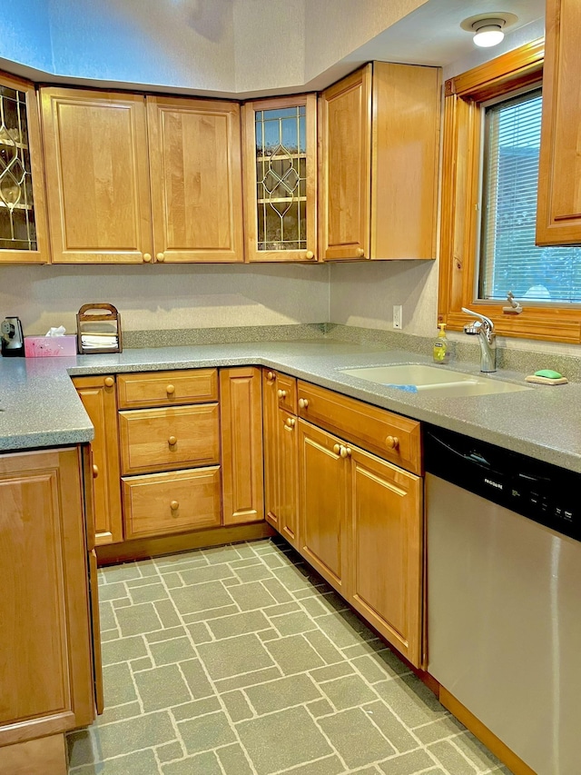 kitchen with dishwasher, glass insert cabinets, brick floor, and a sink