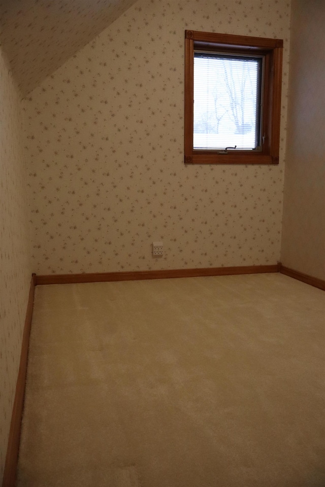 unfurnished room featuring baseboards, carpet flooring, wallpapered walls, and lofted ceiling