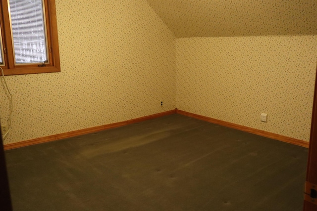 additional living space featuring wallpapered walls, baseboards, and vaulted ceiling