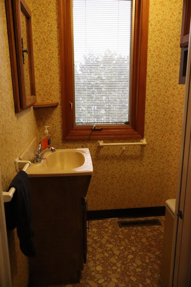 bathroom with visible vents, vanity, and wallpapered walls