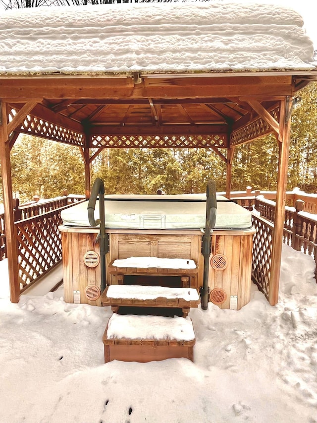 snow covered patio featuring a gazebo and a hot tub