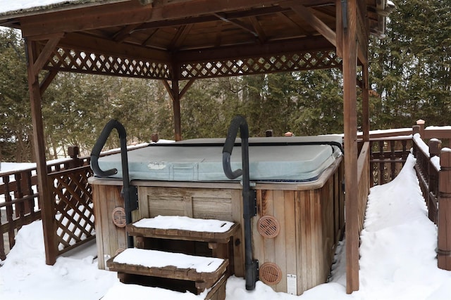 snow covered deck with a gazebo and a hot tub