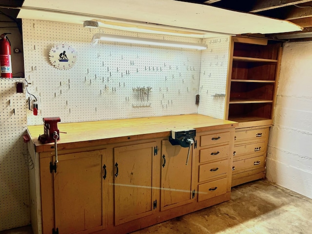 interior space with open shelves, concrete block wall, concrete flooring, and wooden counters