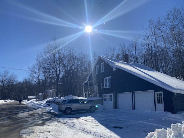 view of snowy exterior featuring an attached garage