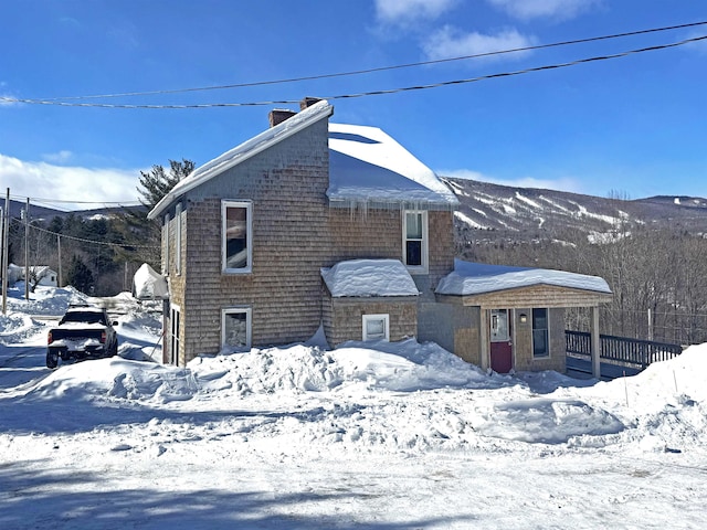 snow covered rear of property with a chimney