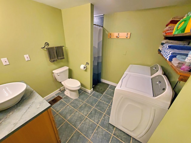 full bath featuring toilet, vanity, washer and dryer, baseboards, and tile patterned floors