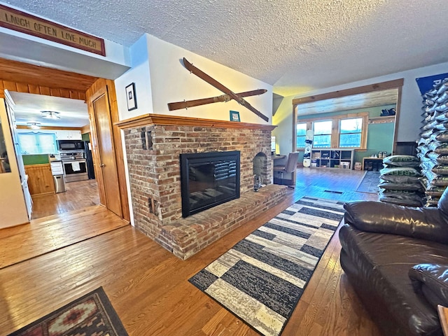 living area with a textured ceiling, a fireplace, and wood finished floors