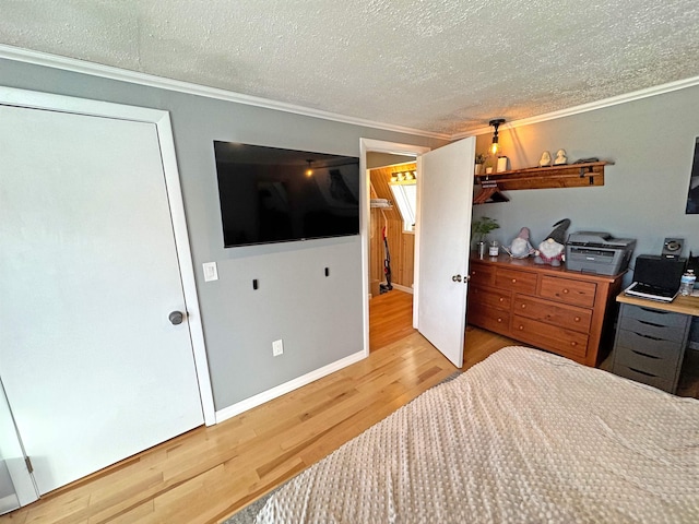 bedroom featuring crown molding, a textured ceiling, baseboards, and wood finished floors