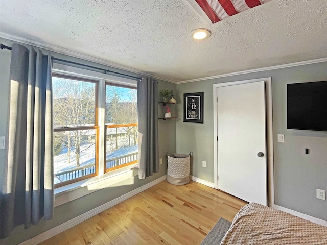 unfurnished bedroom with a textured ceiling, baseboards, wood finished floors, and ornamental molding