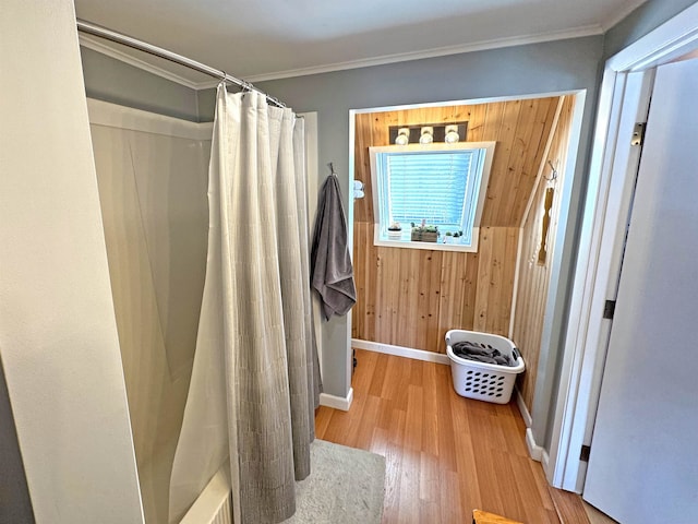 bathroom featuring shower / tub combo, wooden walls, crown molding, and wood finished floors