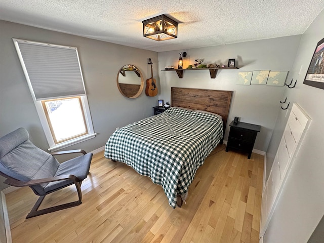 bedroom featuring a textured ceiling, baseboards, and light wood-style floors