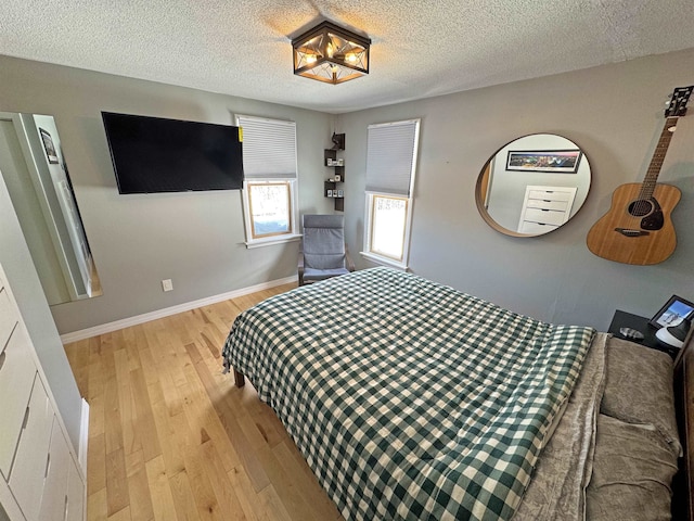 bedroom with light wood-style flooring, baseboards, and a textured ceiling