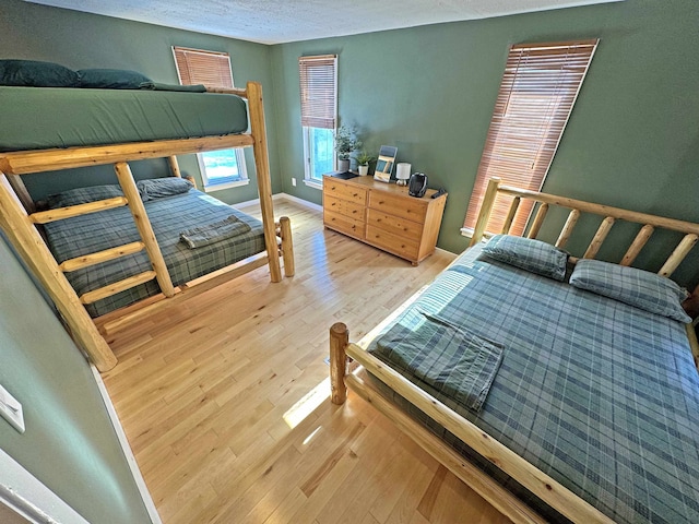 bedroom with a textured ceiling, baseboards, and wood finished floors