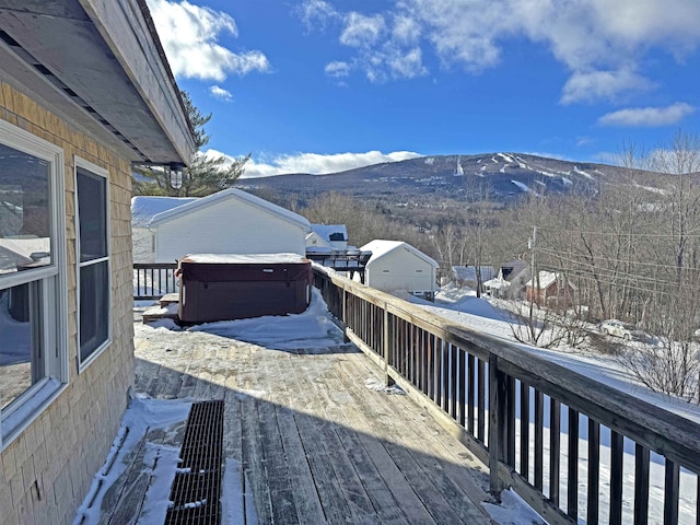 snow covered deck with a hot tub and a mountain view