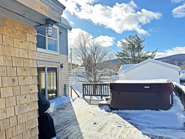 snow covered deck with a mountain view and a hot tub