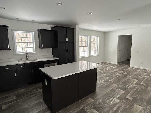 kitchen with dark wood-style flooring, a center island, light countertops, dark cabinetry, and a sink