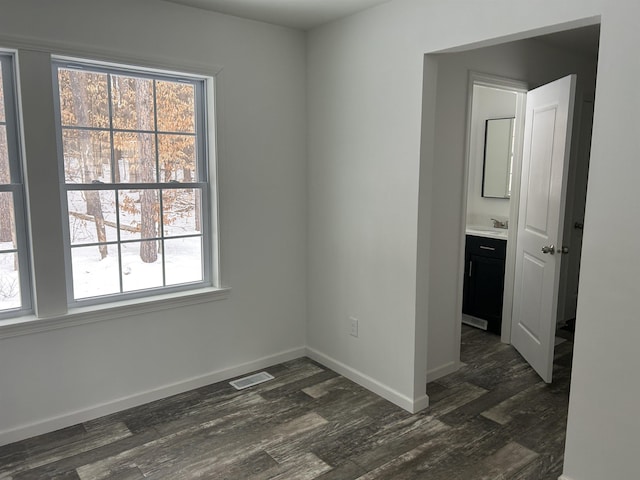 empty room with visible vents, baseboards, and dark wood finished floors