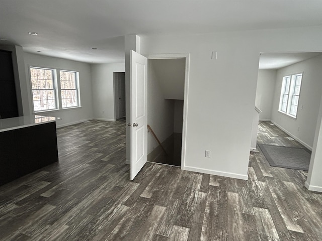 empty room with dark wood-style flooring, plenty of natural light, and baseboards