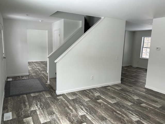 spare room with dark wood-style floors, stairway, and visible vents