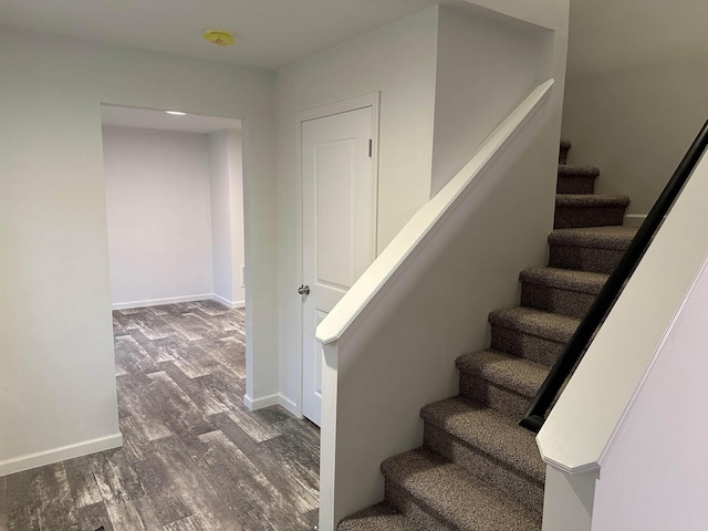 staircase featuring baseboards and wood finished floors