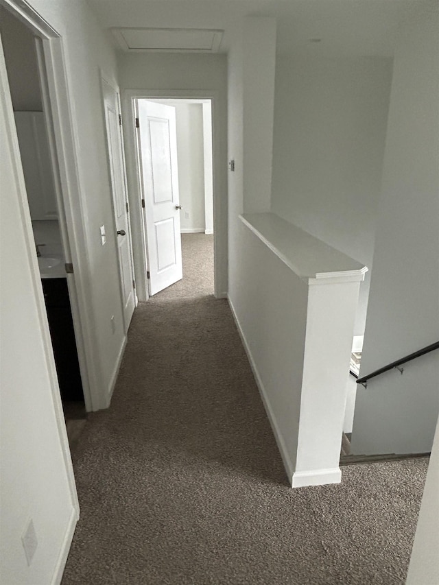 corridor with baseboards, dark carpet, an upstairs landing, and attic access