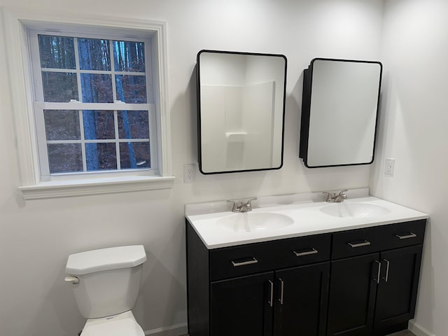 bathroom featuring double vanity, toilet, and a sink