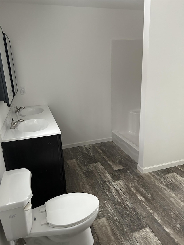 full bath featuring double vanity, baseboards, toilet, and wood finished floors