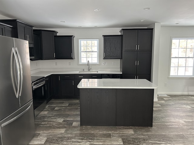 kitchen with a sink, light countertops, appliances with stainless steel finishes, and a kitchen island