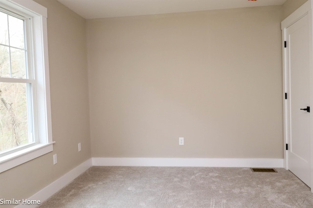 spare room featuring light carpet, plenty of natural light, and baseboards