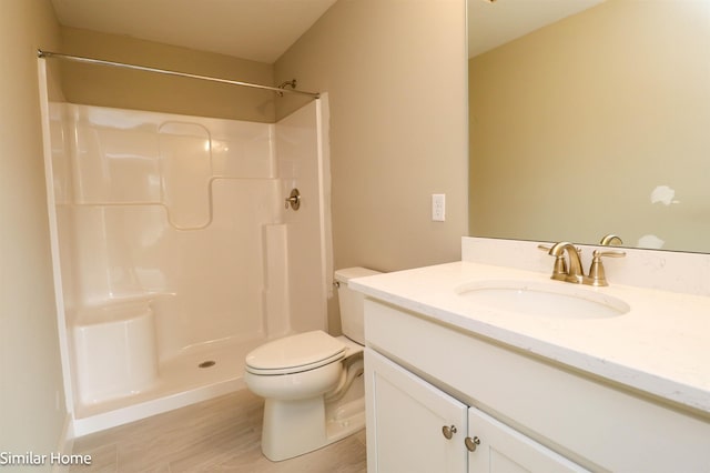 bathroom featuring toilet, a stall shower, wood finished floors, and vanity