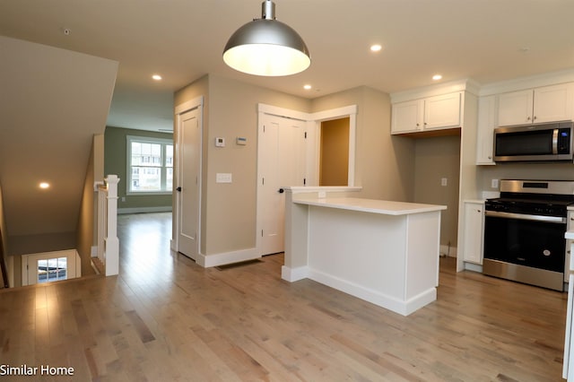 kitchen with stainless steel appliances, light wood-style floors, white cabinets, light countertops, and pendant lighting