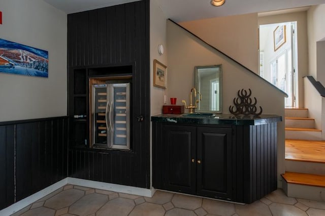 bar with beverage cooler, stairway, wainscoting, and a sink