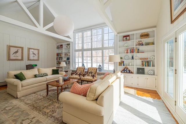 interior space with vaulted ceiling with beams, light wood-style floors, and built in features