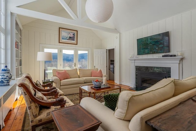 living area featuring a high end fireplace, vaulted ceiling, and hardwood / wood-style floors